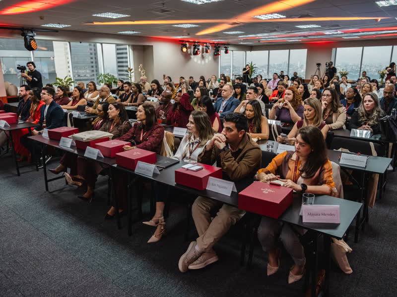 Plateia acompanhando o conteúdo nas mesas do auditório